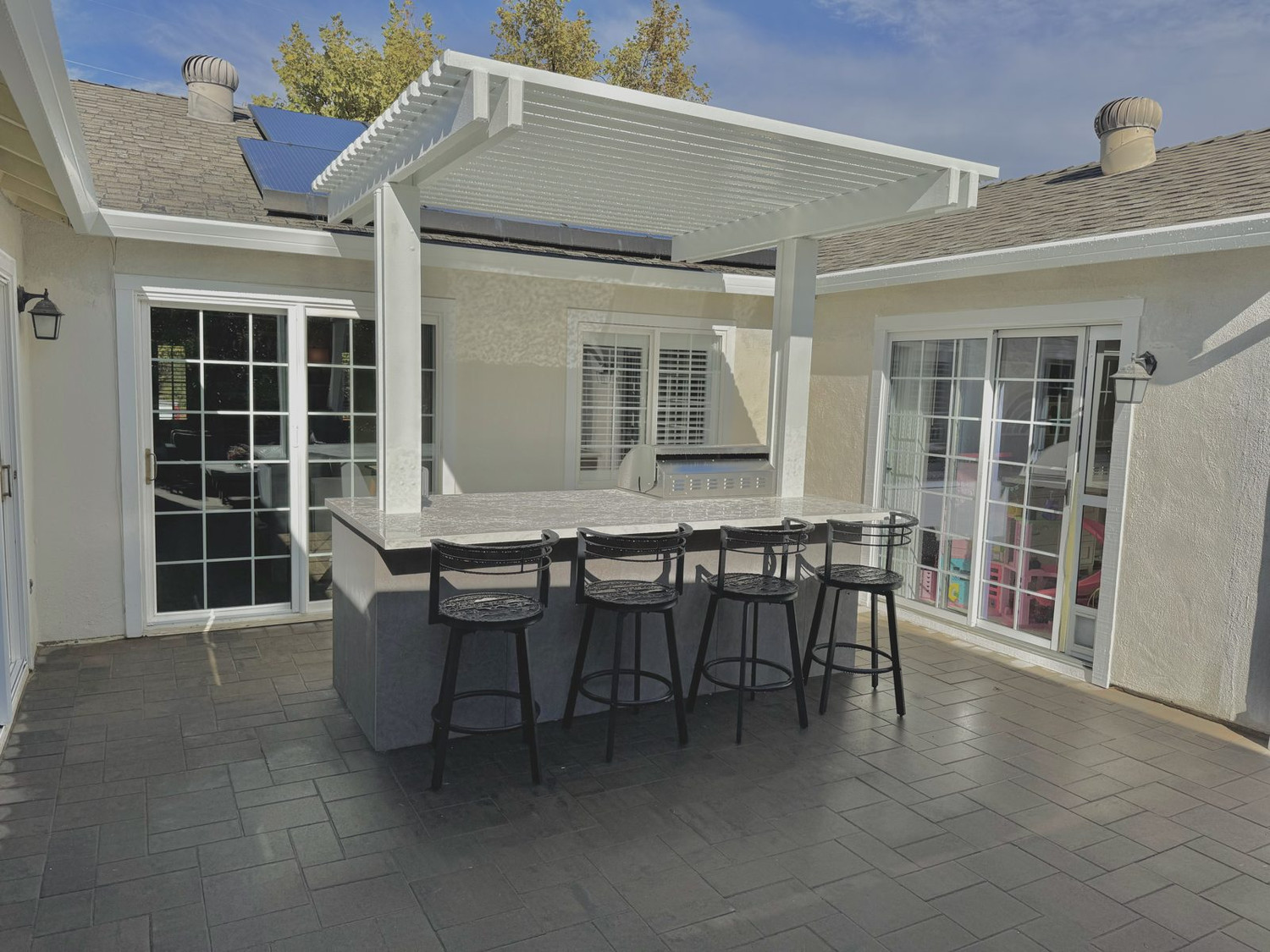 Backyard paver patio with pergola and turf lawn